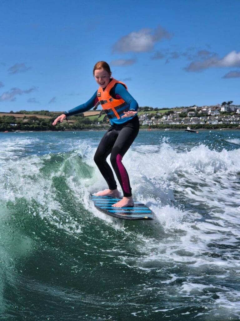 girl wake surfing on a wave created by boat on the camel estuary
