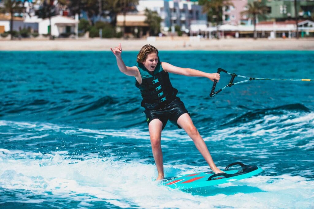boy being towed on a multi position board also called omni board behind a camel ski school motorboat